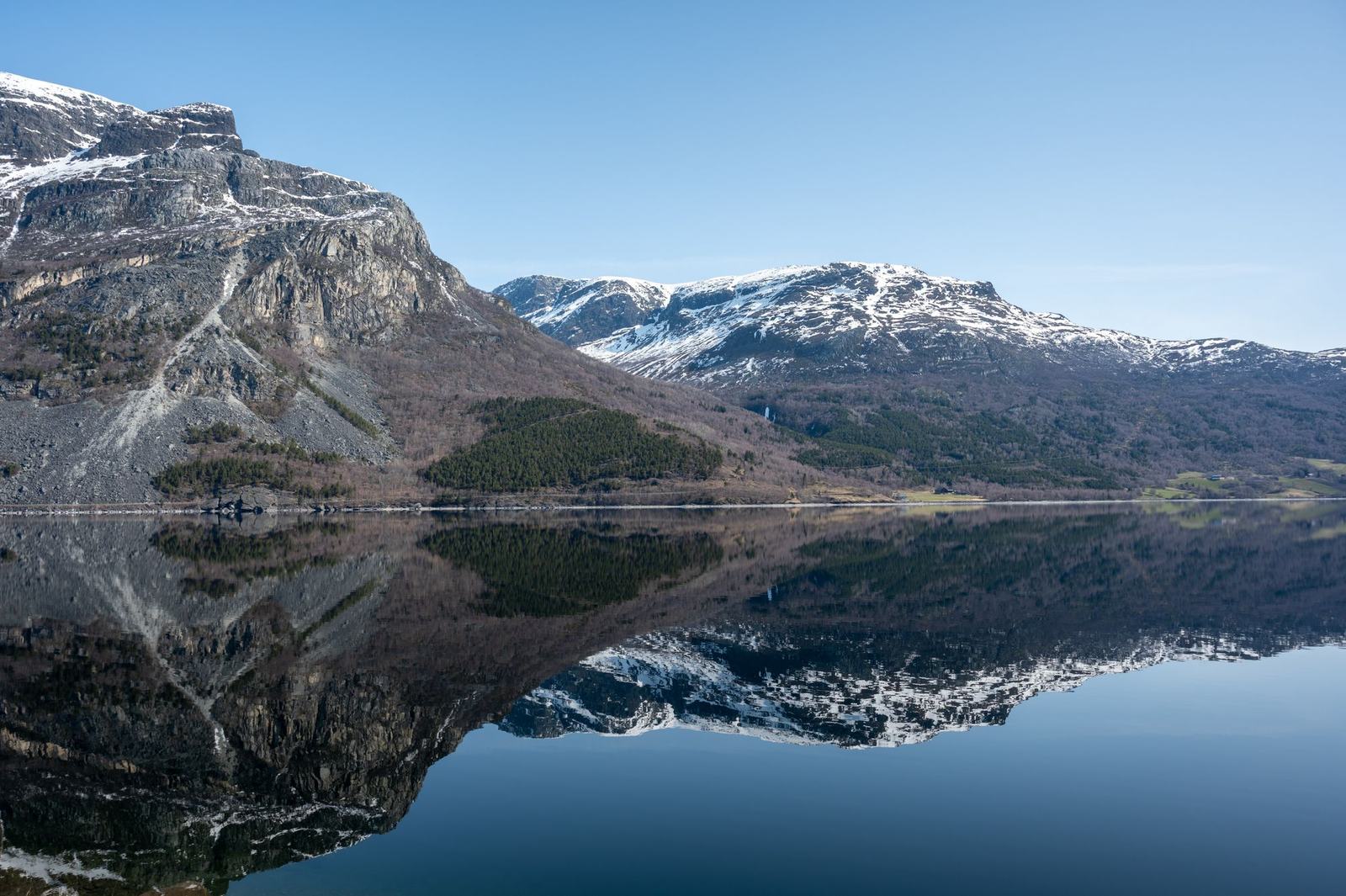 Fjellvann som speiler snødekte fjell